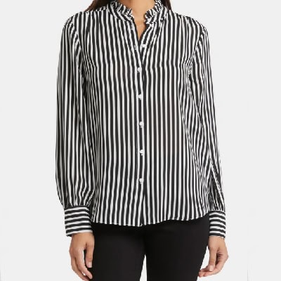 A woman wearing a black and white long sleeve stripe blouse and black pants