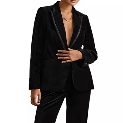 A woman wearing black pants, a black blazer, and gold necklace