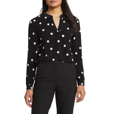 A woman wearing a black and white polka dots long sleeve top and black pants