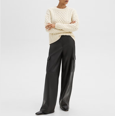 professional young woman wears black leather cargo pants with white cable knit sweater; she's wondering if leather pants can be business casual