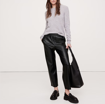 professional young woman wears cropped black leather pants with matching shoes and bag and a beige sweater; she's wondering if leather pants can be business casual