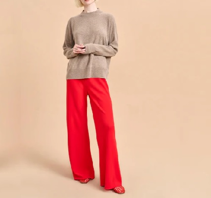 A woman wearing a brown loose long sleeve top and a red wide leg pants