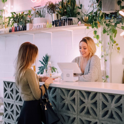 a woman pays for her clothes at a checkout counter; she just might be looking for the best places to buy work clothes on a budget
