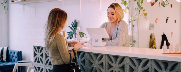 a woman pays for her clothes at a checkout counter; she just might be looking for the best places to buy work clothes on a budget