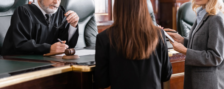 a young female lawyer speaks with a judge and an older woman lawyer; they might just be talking about the best courtroom attire for women lawyers