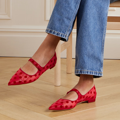 woman wears red polka dot mesh mary jane shoes with leather cap toe beneath the mesh