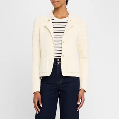 A woman wearing a cream blazer, striped top, and dark blue jeans