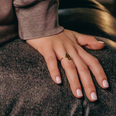 woman with healthy nails leans against a couch