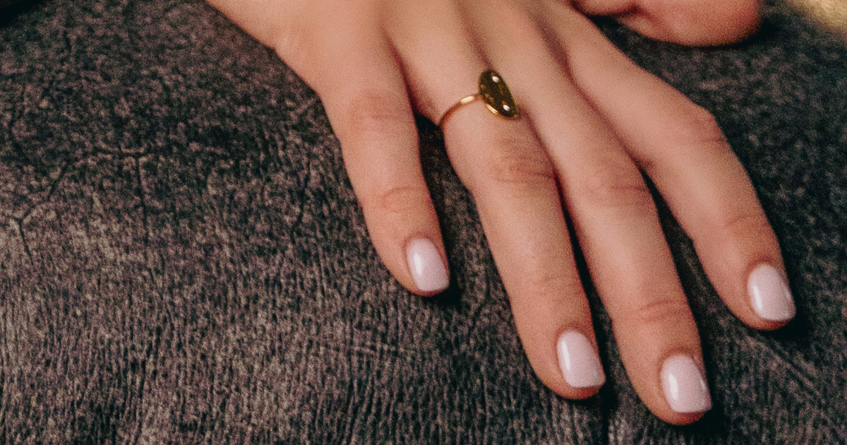 woman with healthy nails leans against a couch