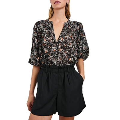 woman wears dark floral puff sleeve blouse with loose black shorts