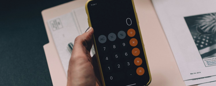 woman holds calculator above a pink folder with papers; she just might be using some of the best budgeting resources like books and apps