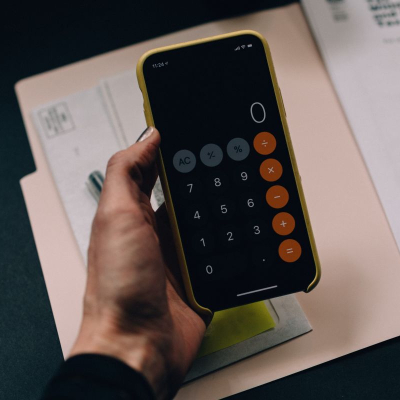 woman holds calculator above a pink folder with papers; she just might be learning how to budget