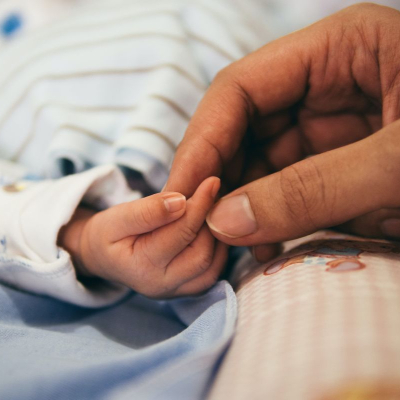 woman holds newborn baby's hand