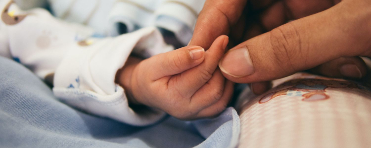 woman holds newborn baby's hand