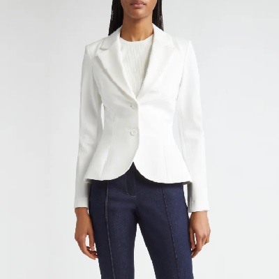 A woman wearing a white blazer top and denim pants