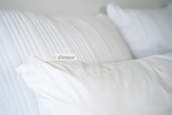 Three white pillows, one with an allergy cover labeled Allerease