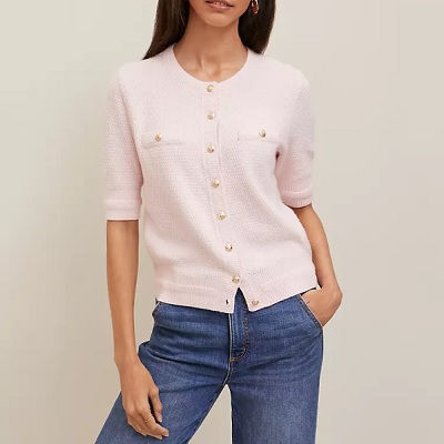 A woman wearing a light pink cardigan top and denim pants