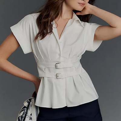 A woman wearing a white top with collar and double buckle