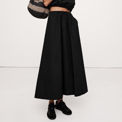 A woman wearing a black maxi skirt and black shoes