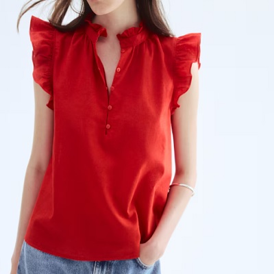 A woman wearing a red linen blouse and denim pants
