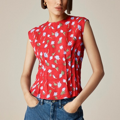 A woman wearing a red daisy printed top and denim pants