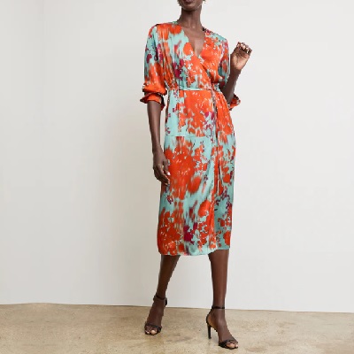 A woman wearing a orange and blue floral wrap dress with black heeled sandals