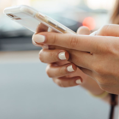 woman wearing white nail polish types on her phone, she just might be creating a best prices list or spreadsheet