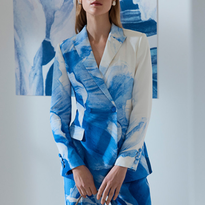 female executive wears blue and white suit with large peony pattern; she is holding a bag