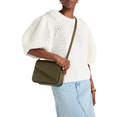 Black woman carries olive structured bag across her body; she is wearing a white puffy-sleeved sweater