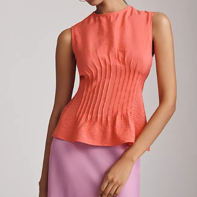 A woman wearing a peach sleeveless top and pink skirt