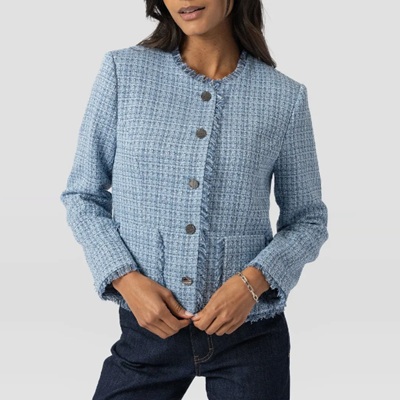 A woman wearing a light blue boucle jacket and dark blue jeans