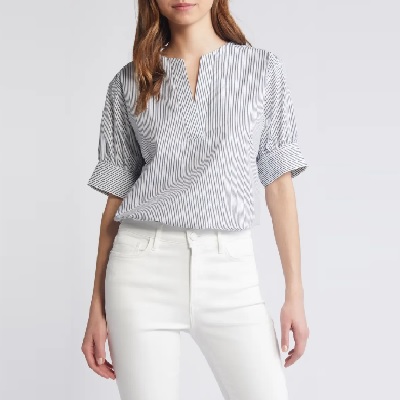A woman wearing a white black stripe top and white jeans