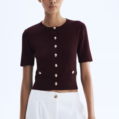 A woman wearing a maroon short sleeve top and white pants