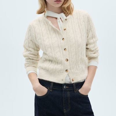 A woman wearing a white top under an ivory cardigan with dark blue denim pants