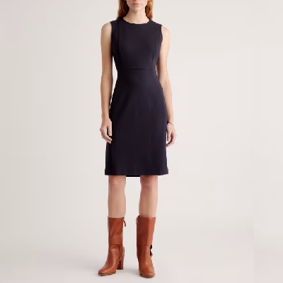 A woman wearing a black sleeveless dress and brown boots