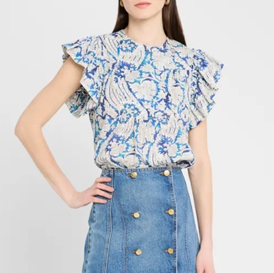 A woman wearing a blue and white printed top and denim skirt