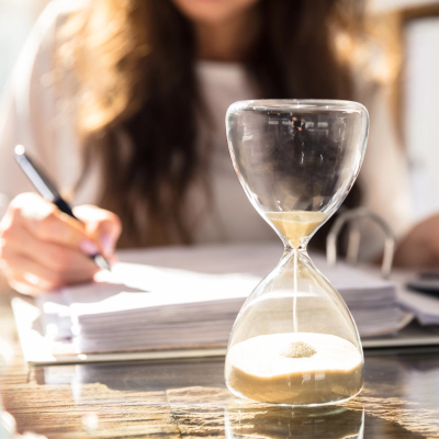 businesswoman works while an hourglass runs out of time
