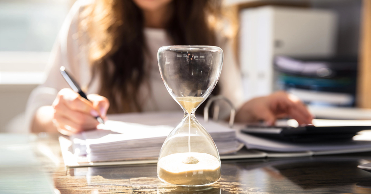 businesswoman works while an hourglass runs out of time