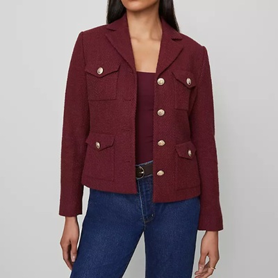 A woman wearing a maroon top with maroon blazer jacket and dark blue denim pants