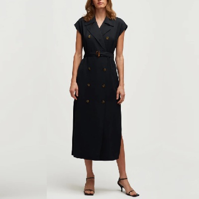A woman wearing a black, trench-style dress with black heels