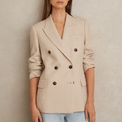 A woman wearing a checkered light brown blazer