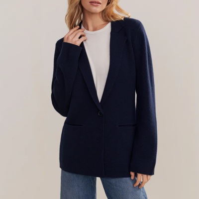 A woman wearing a white top and dark blazer with denim pants