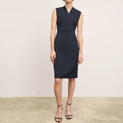 A woman wearing a black sleeveless dress with black pencil cut sandals