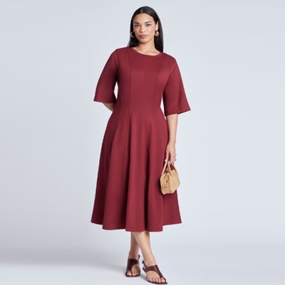A woman wearing a burgundy midi dress and brown sandals, carrying a light brown suede bag
