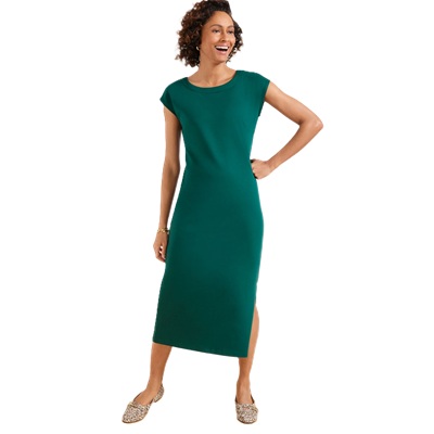 A woman wearing a green cap-sleeve dress with animal-print shoes