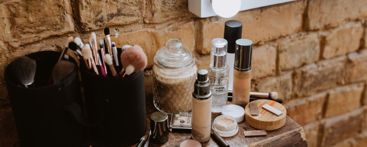 lotions and serums sit on a wooden counter in front of a light; they just might be beauty products bought on repeat