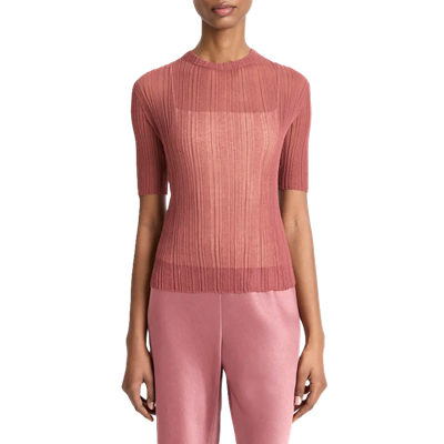 woman wears soft pink open-stitch knit sweater with a white camisole beneath