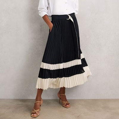 A woman wearing a white top and navy/ivory midi skirt and brown sandals