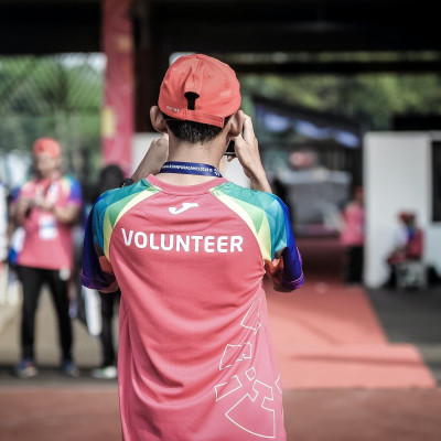 person wearing a red shirt that reads VOLUNTEER is taking a picture of a group of people; they just might have been too busy to volunteer