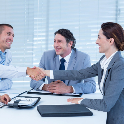 young female job applicant shakes hands with a group of business people; she just might be having an on-campus interview in law school